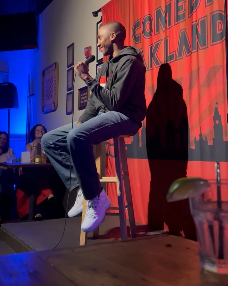 McKinley Malbrough III on stage at Comedy Oakland, holding the mic